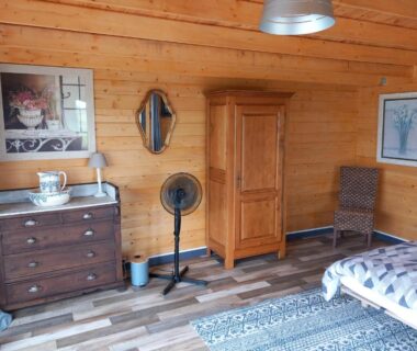 Chambre en bois avec armoire commode et lit dans le Chalet chez le breton des marais