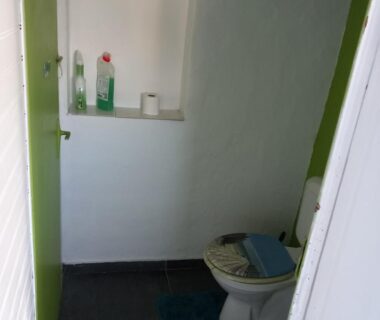 WC avec étagère produits ménagers et rouleau de papier toilette dans le Chalet chez le breton des marais