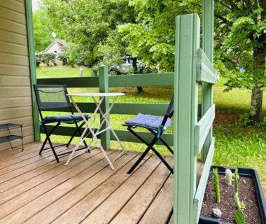 Terrasse avec table et chaises donnant sur jardin arboré du Chalet cosy au cœur de la nature