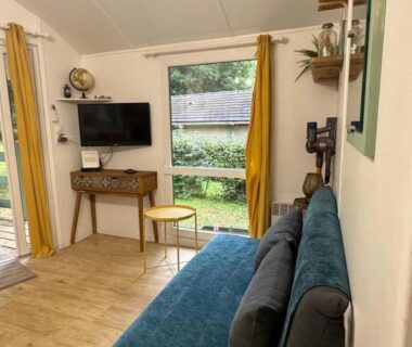 Salon avec canapé bleu et baie vitrée dans le Chalet cosy au cœur de la nature
