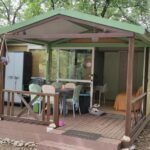 Terrasse en bois et coin repas sous les arbres du Chalet dans Camping 3 étoiles à Vogüé