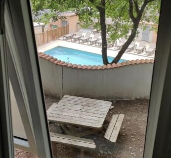 Depuis la fenêtre piscine et table de jardin au Chalet dans Camping 3 étoiles à Vogüé