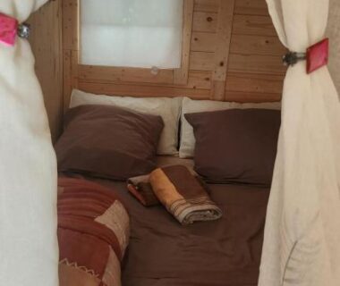 Chambre en bois avec lit et rideaux dans le Chalet en bois avec Jacuzzi Privé et Piscine