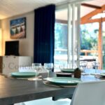 Séjour avec table dressée près de baie vitrée donnant sur terrasse du Chalet en bord de plage