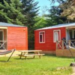 Pelouse avec deux chalets en bois et hamacs au Camping les Sapins