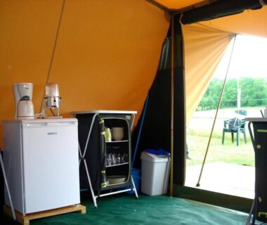 Intérieur de tente avec frigo cafetière et vaisselle au Camping les Sapins