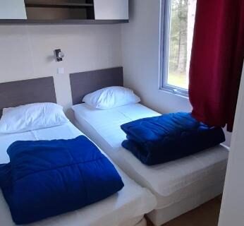 Chambre avec deux lits simples dans le mobil home au Camping les Sapins