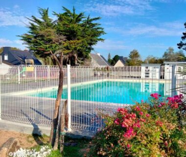 Piscine extérieure clôturée avec fleurs et chalets en arrière plan du Chalet mobil-home