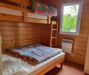 Chambre en bois avec lits superposés et fenêtre dans le Chalet nature et lac dans parc résidentiel de loisirs
