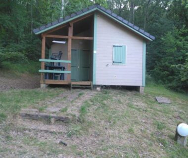 Chalet en bois entouré de sous-bois avec terrasse et escaliers au Chalet nature et lac dans parc résidentiel de loisirs