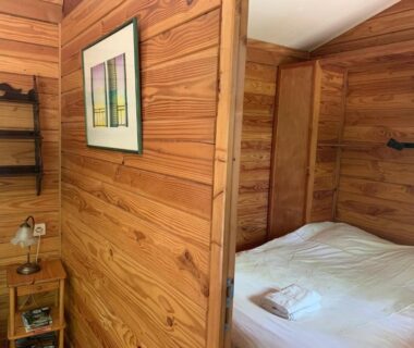 Intérieur de chalet en bois avec lit et chevet dans les Chalets & Camping Villa Mayari