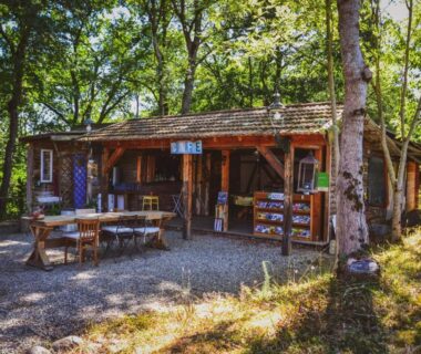 Buvette en bois sous les arbres avec tables et chaises à Chalets & Camping Villa Mayari