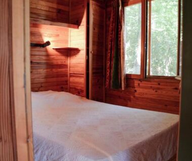 Chambre en bois avec lit et fenêtre à Chalets & Camping Villa Mayari