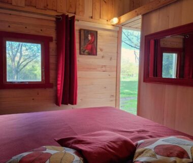 Intérieur de chalet avec lit et fenêtres dans les Chalets de l'Oasienne