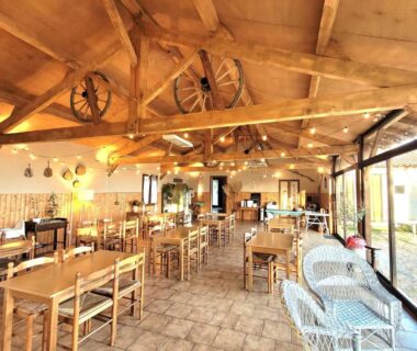 Salle à manger avec tables et poutres apparentes des Chalets de l'Oasienne