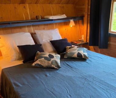 Chambre en bois avec lit double et lampes dans les Chalets de l'Oasienne