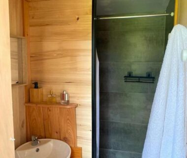 Salle de bains en bois avec lavabo et douche dans les Chalets de l'Oasienne