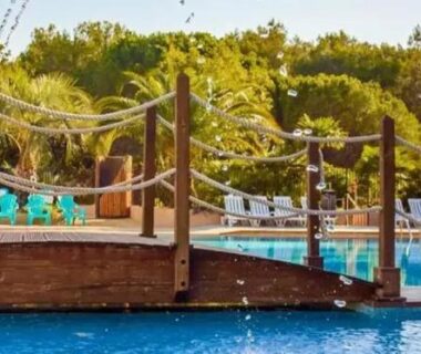 Piscine avec ponton en bois et jeux aquatiques aux Chalets met buitenkeuken op Camping Leï Suves JoyCasa