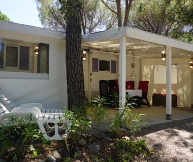 Terrasse couverte avec chaises longues et coin repas au chalet Chalets met buitenkeuken op Camping Leï Suves JoyCasa