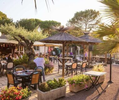 Terrasse extérieure avec tables et parasols au Camping Leï Suves JoyCasa