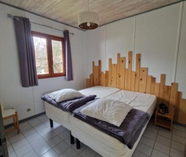 Chambre avec deux lits et tête de lit en bois au camping Chanteduc