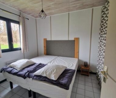 Chambre avec deux lits et fenêtre donnant sur jardin du camping Chanteduc
