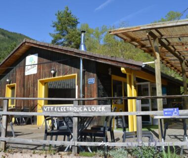 Façade en bois avec terrasse et enseigne de location de VTT au camping Chanteduc
