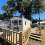 Terrasse en bois avec mobil-home et arbres du Charmant Mobil-home 3 chambres de Valérie et Hermann Camping 4 étoiles