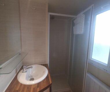 Salle de bain avec lavabo et cabine de douche dans le Charmant Mobil-home proche de la mer