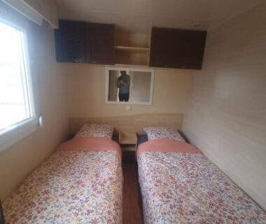 Chambre avec deux lits et fenêtre dans le mobil-home Charmant Mobil-home proche de la mer