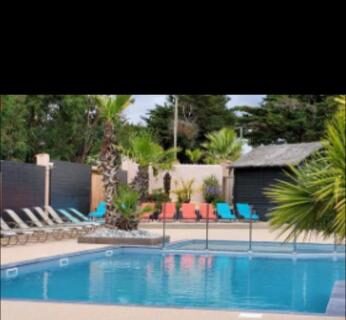 Piscine extérieure avec transats et parasols au Charmant Mobil-home proche de la mer