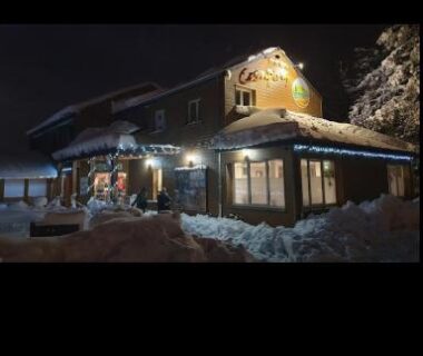 Façade nocturne enneigée d'un chalet en bois du Charmant Mobil home style chalet