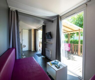 Intérieur avec canapé et terrasse donnant sur verdure au Charmant camping Familiale 3 Etoiles