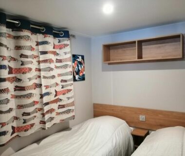 Chambre avec deux lits simples et rideaux dans le Charmant mobil-home Pont-Aven