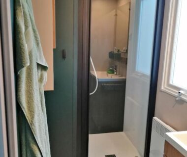 Salle de bains avec douche vitrée et serviette du Charmant mobil-home Pont-Aven