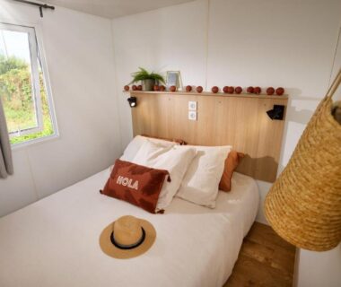 Intérieur chambre avec lit, coussins et chapeau au Château de l'Hom