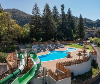 Piscine extérieure avec toboggans transats et parasols au Château de l'Hom