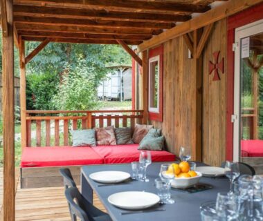 Terrasse couverte avec table dressée et banquette rouge du Château de l'Hom