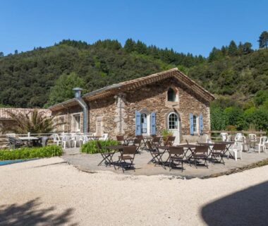 Terrasse avec tables et chaises devant bâtiment en pierre du Château de l'Hom