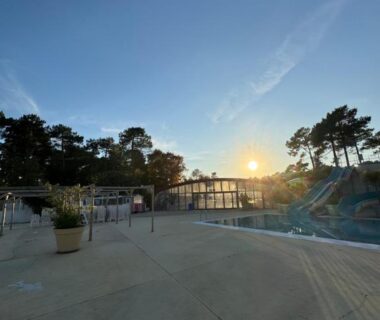 Piscine extérieure avec toboggans et pins au coucher du soleil au camping Chez Greg et ilhem