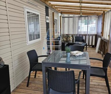 Terrasse couverte avec table, chaises et canapé dans le mobil-home Chez Sandy et Romain