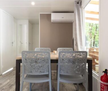 Intérieur coin repas avec deux chaises et climatisation dans le mobil home Chez gaby