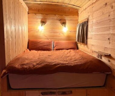 Intérieur de roulotte avec lit en bois dans la Chicken roulotte des 3 cèdres