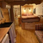 Intérieur de roulotte en bois avec lit kitchenette et canapé dans la Chicken roulotte des 3 cèdres