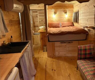 Intérieur de roulotte en bois avec lit kitchenette et canapé dans la Chicken roulotte des 3 cèdres