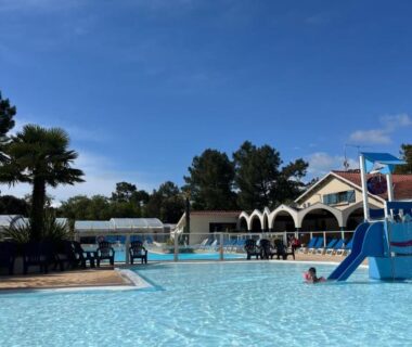 Piscine extérieure avec toboggan et palmiers au Clearedtochill Mobilhome 6P Camping Siblu Bois Dormant