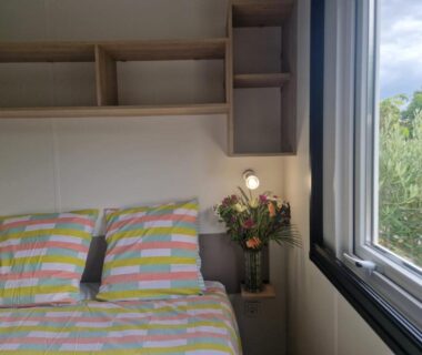 Intérieur chambre avec lit et fenêtre dans le mobil-home Clim, piscine, animations, concerts, jeux enfant