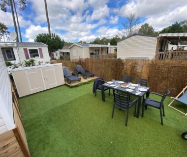 Terrasse avec table et chaises sur pelouse synthétique au camping Coeur Des Sables