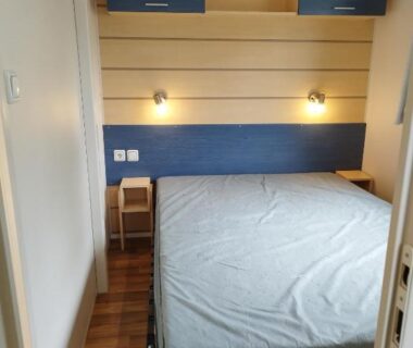 Chambre avec lit double lampes murales et rangements dans l'hébergement Comme Chez Vous Au Camping Des Iscles