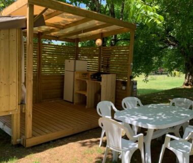 Terrasse couverte avec kitchenette et table extérieure au camping Cop’campétoiles